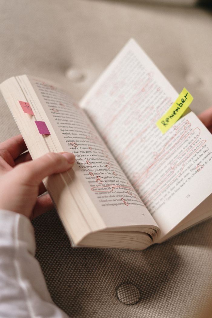 Close-up of a book with annotations and sticky notes with 'Remember'.